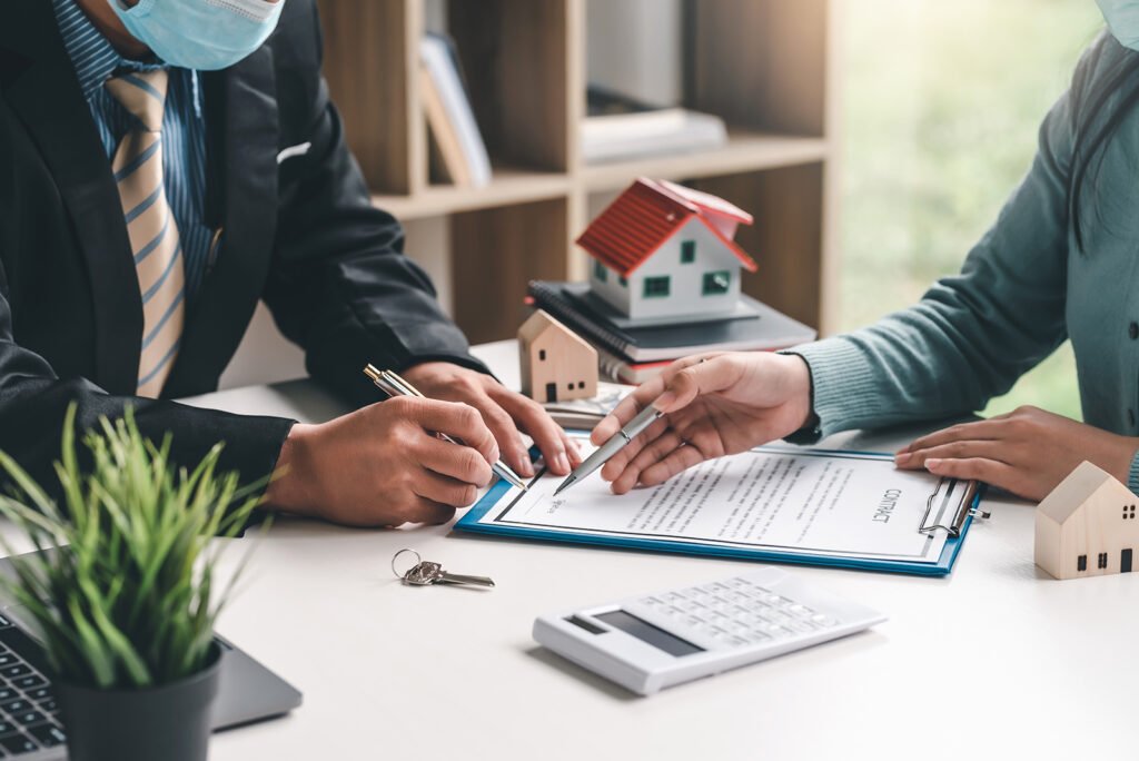 Close-up of real estate agent hand pointing at document signing contract house purchase agreement at the office.